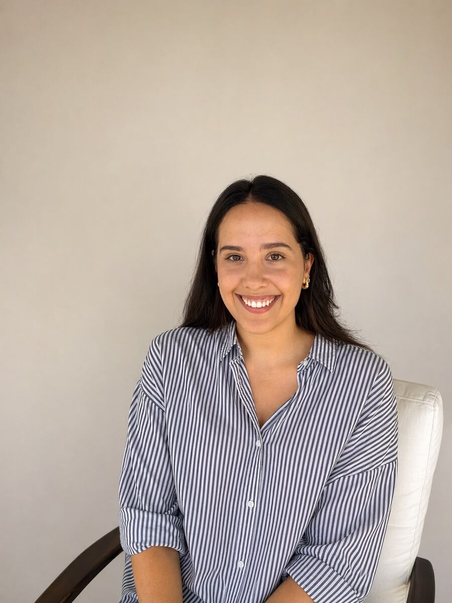 Laura Alcântara, psicóloga, sorrindo, sentada em uma poltrona